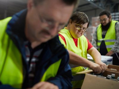 Drei Arbeiter packen Flaschen in Kartons