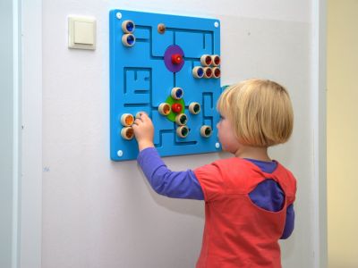 Ein kleins Mädchen macht ein buntes Rätsel an der Wand
