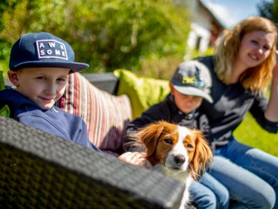 Kinder sitzen mit einem Hund auf einer Bank