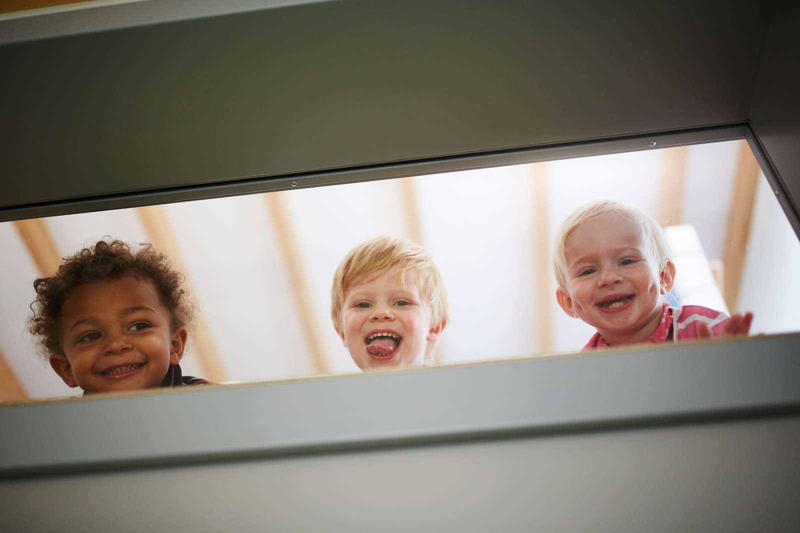 Kleine Kinder schauen durch ein Fenster und freuen sich